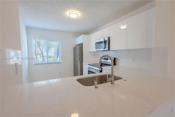 a kitchen with a sink a stove cabinets and a window
