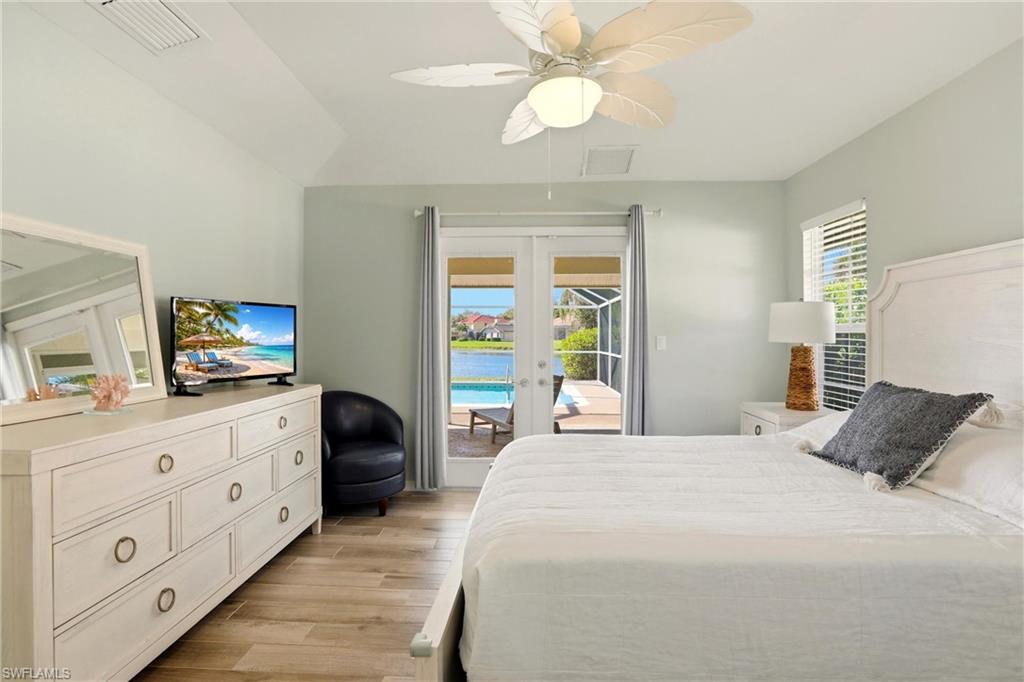 4282 Longshore Way North Naples, FL 34119 - Photo 20 of 43 Bedroom featuring french doors, access to outside, light wood finished floors, ceiling fan, and vaulted ceiling
