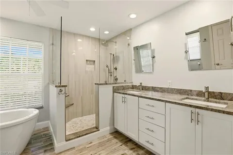 a spacious bathroom with a granite countertop sink mirror and bathtub