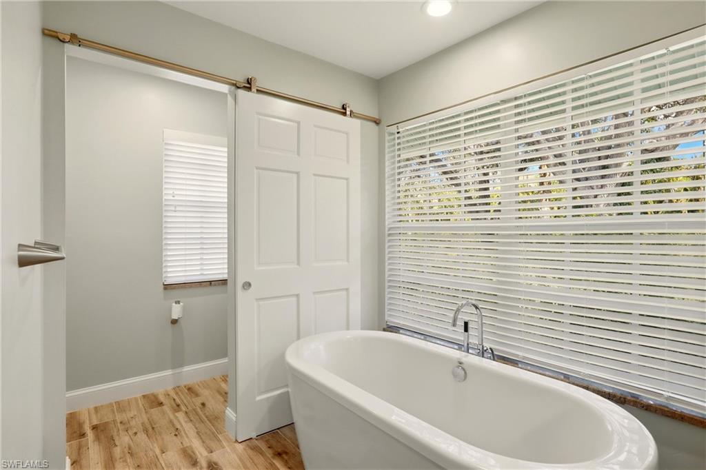 4282 Longshore Way North Naples, FL 34119 - Photo 24 of 43 Bathroom with light wood-style floors and a freestanding bath