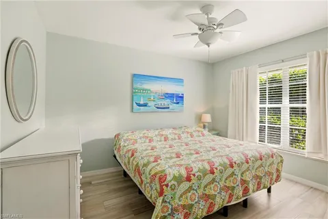 a bedroom with a bed a dresser and a chandelier