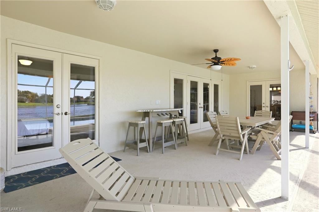 4282 Longshore Way North Naples, FL 34119 - Photo 31 of 43 View of patio / terrace featuring french doors, outdoor dining space, ceiling fan, and a water view