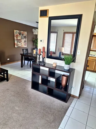 a living room with furniture and a mirror next to a window