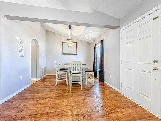 a dining room with wooden floor a chandelier a wooden table and chairs