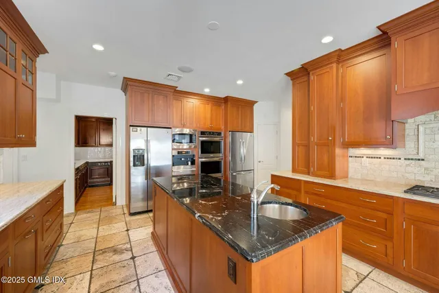 a kitchen with stainless steel appliances granite countertop a sink a stove and a refrigerator