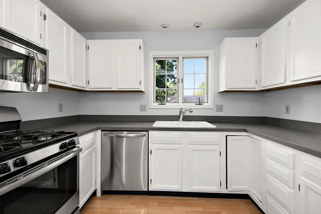 a kitchen with white cabinets and appliances