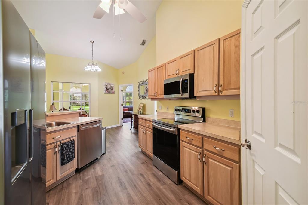 12728 Flamingo Parkway Spring Hill, FL 34610 - Photo 13 of 54 a kitchen with stainless steel appliances granite countertop a stove top oven a sink dishwasher a refrigerator and a dining table with wooden floor