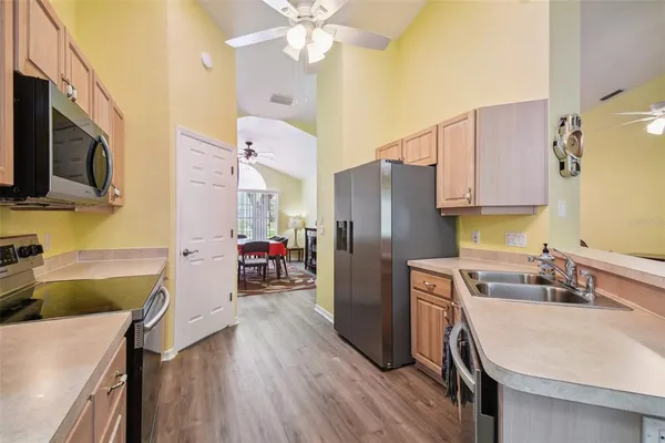 a open kitchen with stainless steel appliances granite countertop a stove top oven a sink dishwasher a dining table and chairs with wooden floor