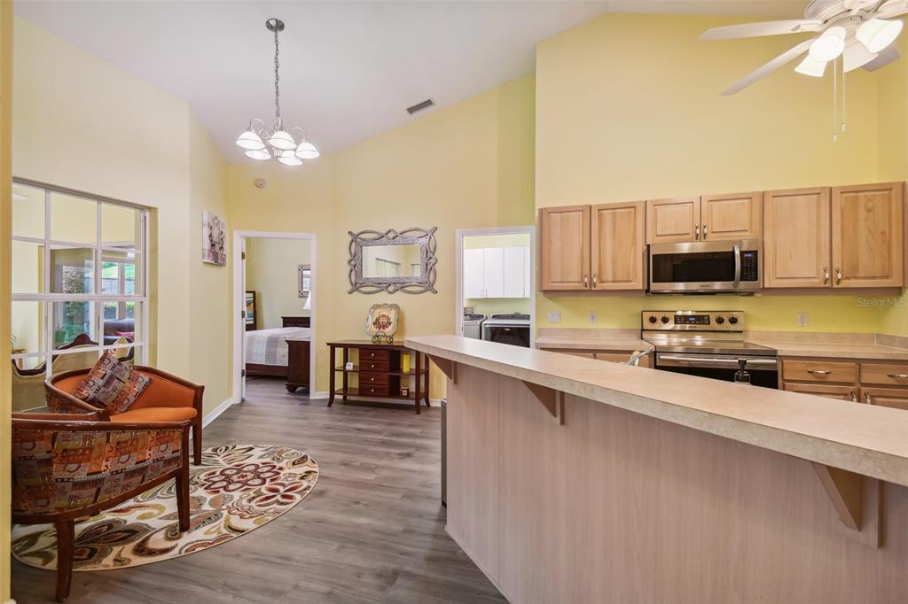 12728 Flamingo Parkway Spring Hill, FL 34610 - Photo 19 of 54 a open kitchen with stainless steel appliances granite countertop a stove top oven a sink dishwasher a dining table and chairs with wooden floor