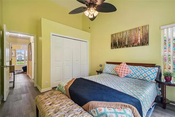 a bedroom with a bed and dresser with wooden floor