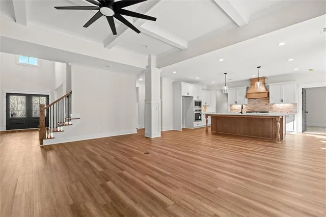 a view of a kitchen with kitchen island a sink wooden floor and appliances