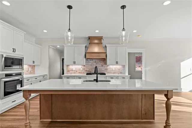 a kitchen with stainless steel appliances granite countertop a sink a stove and a wooden floors