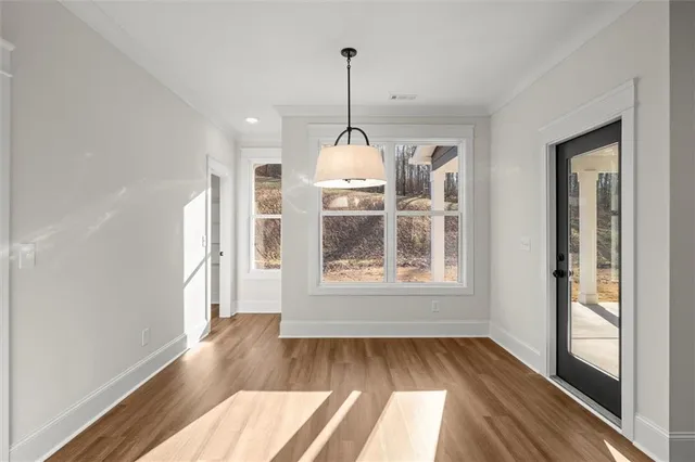 a view of a room with wooden floor chandeliers and kitchen view