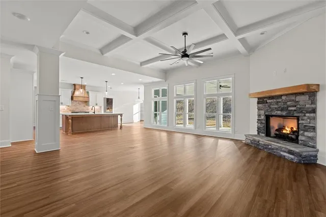 a view of an empty room with wooden floor fireplace and a window