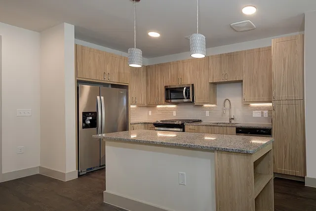 a kitchen with granite countertop a refrigerator a sink a stove a microwave a counter space and cabinets