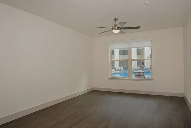 an empty room with a window and ceiling fan