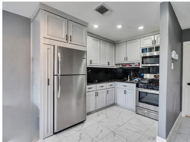 a kitchen with stainless steel appliances granite countertop a refrigerator and a stove top oven