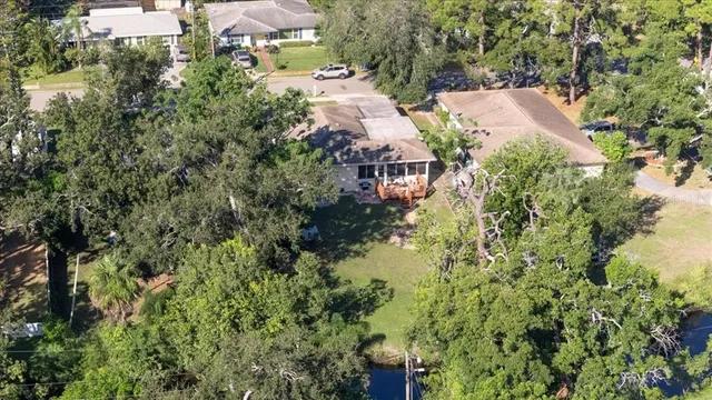 an aerial view of residential house with outdoor space and trees all around