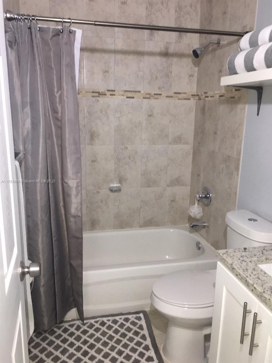 1990 Northwest 4th Court, Unit 8 Miami, FL 33136 - Photo 16 of 19 a bathroom with a granite countertop bathtub shower and toilet