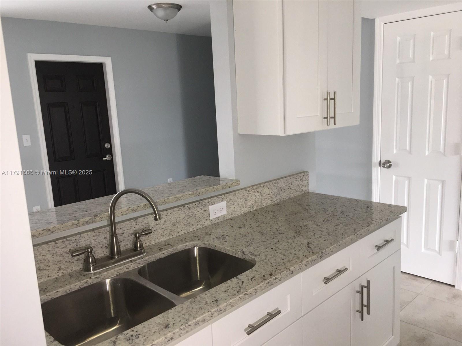 1990 Northwest 4th Court, Unit 8 Miami, FL 33136 - Photo 17 of 19 a kitchen with granite countertop white cabinets and sink