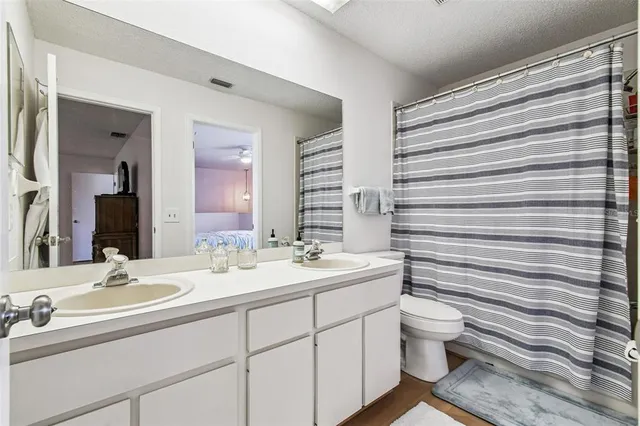 a bathroom with a double vanity sink toilet and mirror
