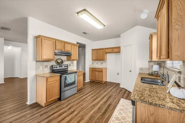 a kitchen with stainless steel appliances granite countertop sink stove refrigerator dining table and chairs
