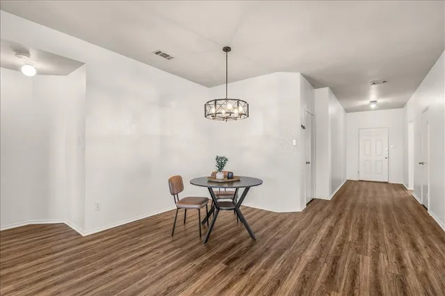 a view of a room with wooden floor table and chairs