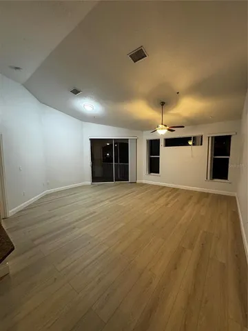an empty room with wooden floor and windows