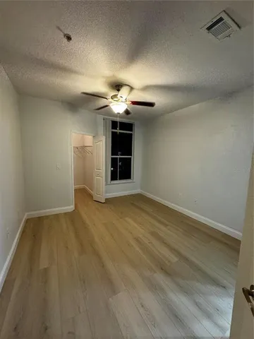 an empty room with wooden floor chandelier and windows