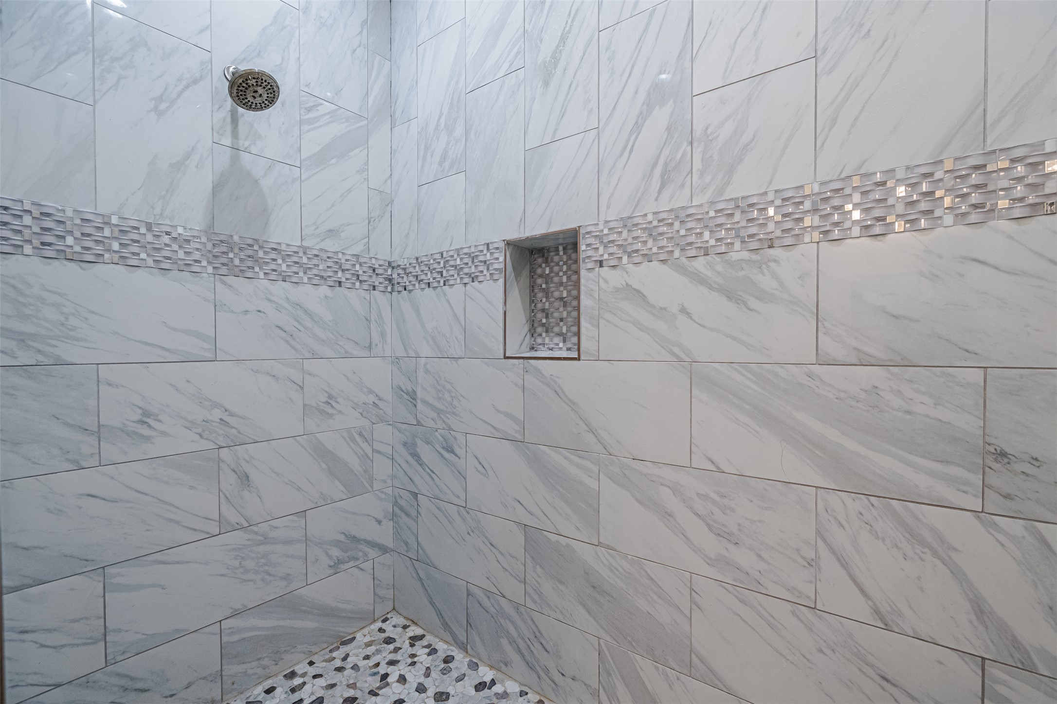 1354 Old Pin Oak Road Paige, TX 78659 - Photo 15 of 37 The shower features large format tiles with a subtle grey veining, a decorative mosaic tile band, and a built-in shower niche