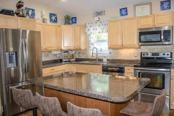 a kitchen with stainless steel appliances granite countertop a sink a stove and a refrigerator