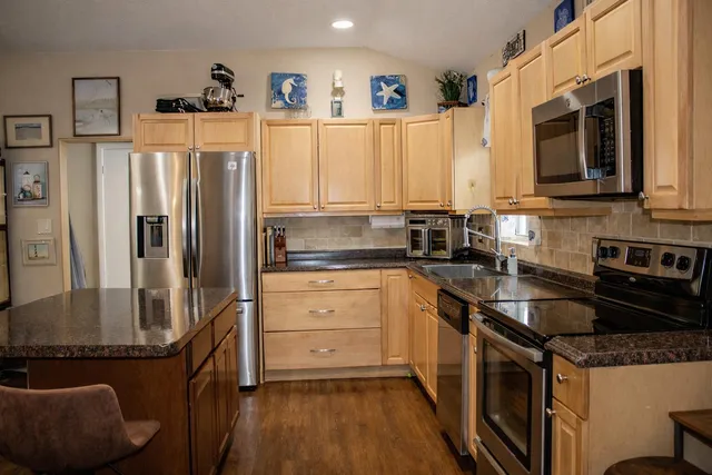 a kitchen with granite countertop a refrigerator stove and sink