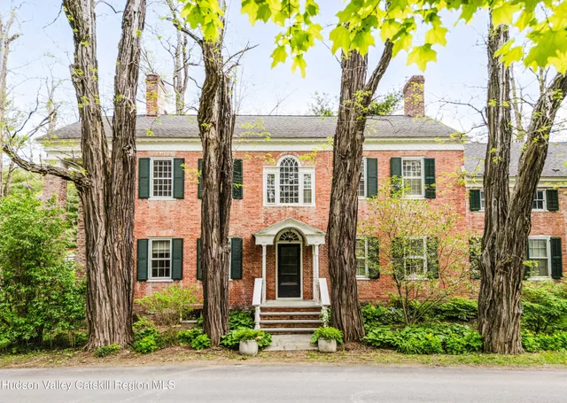 front view of a brick house with a large windows and a large tree