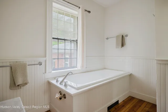 a bedroom with a bed a table and chair with the wooden floor