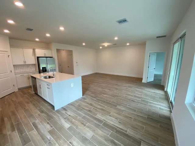 a large room with kitchen island a sink wooden floor and a refrigerator