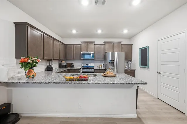 a kitchen with stainless steel appliances granite countertop a sink refrigerator and cabinets