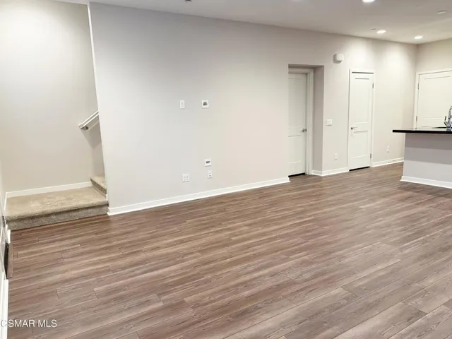 a large kitchen with stainless steel appliances a large counter top and wooden floors