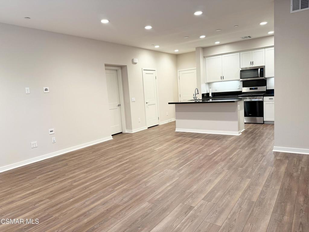 215 Red Brick Drive, Unit 5 Simi Valley, CA 93065 - Photo 5 of 30 a large kitchen with stainless steel appliances a large counter top and wooden floors