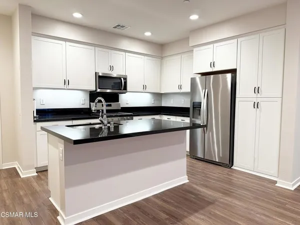 a kitchen with granite countertop a sink stainless steel appliances and white cabinets