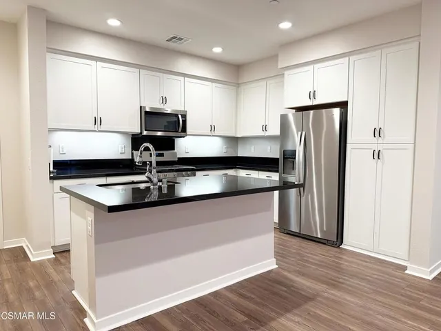 a kitchen with granite countertop a sink stainless steel appliances and white cabinets
