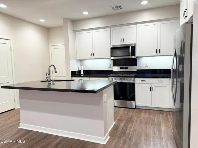 a kitchen with granite countertop a sink cabinets and wooden floor
