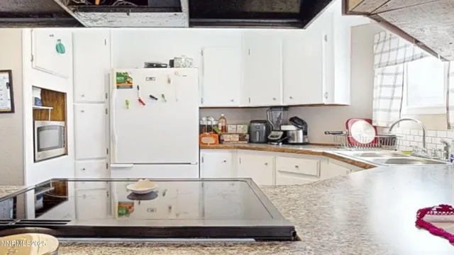 a kitchen with a refrigerator and white cabinets