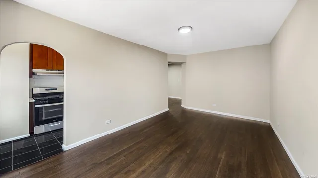 an empty room with wooden floor closet and windows