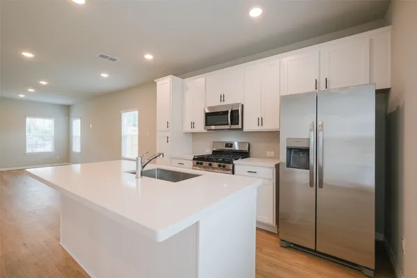 a kitchen with kitchen island a sink stainless steel appliances and refrigerator