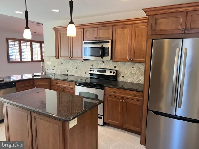 a kitchen with kitchen island granite countertop a sink a counter space appliances and cabinets