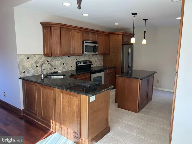 a kitchen with granite countertop a sink a counter top space appliances and cabinets