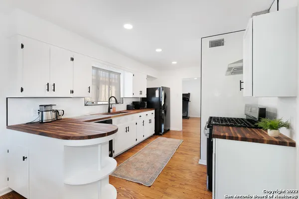 a kitchen with stainless steel appliances kitchen island granite countertop a refrigerator a sink a stove and white cabinets