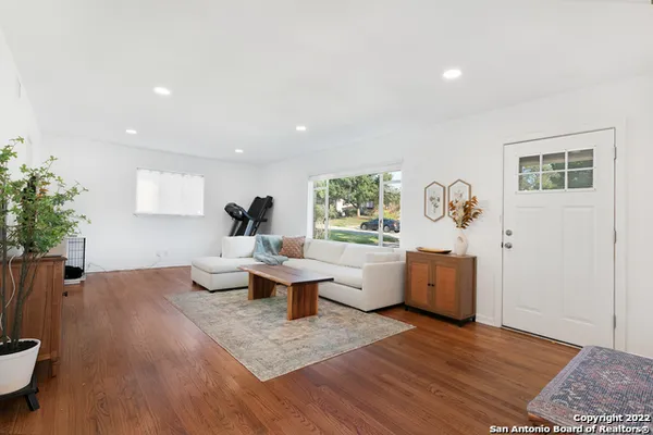 a living room with furniture a potted plant and a wooden floor