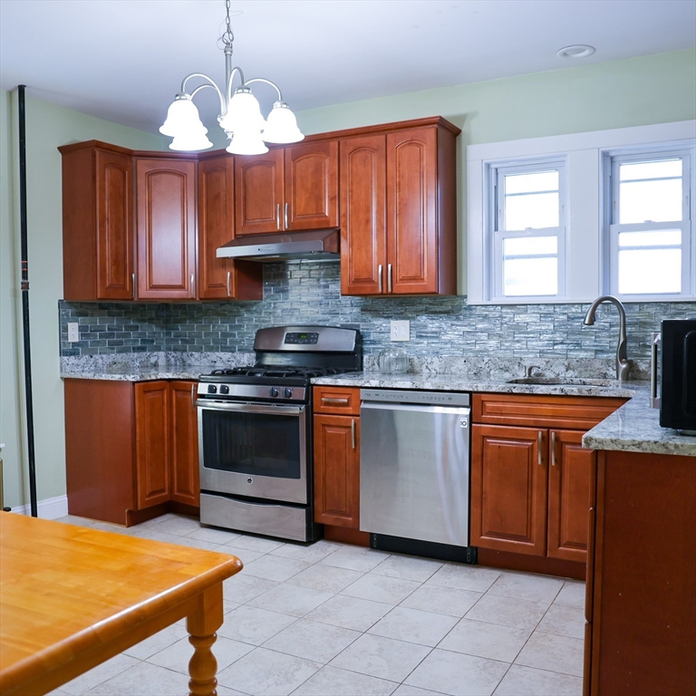 186 Powell Street Lowell, MA 01851 - Photo 16 of 42 a kitchen with stainless steel appliances granite countertop a stove a sink and a microwave