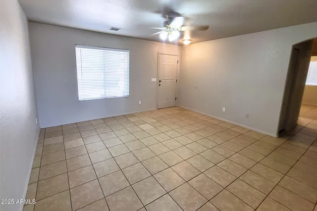 an empty room with windows and ceiling fan